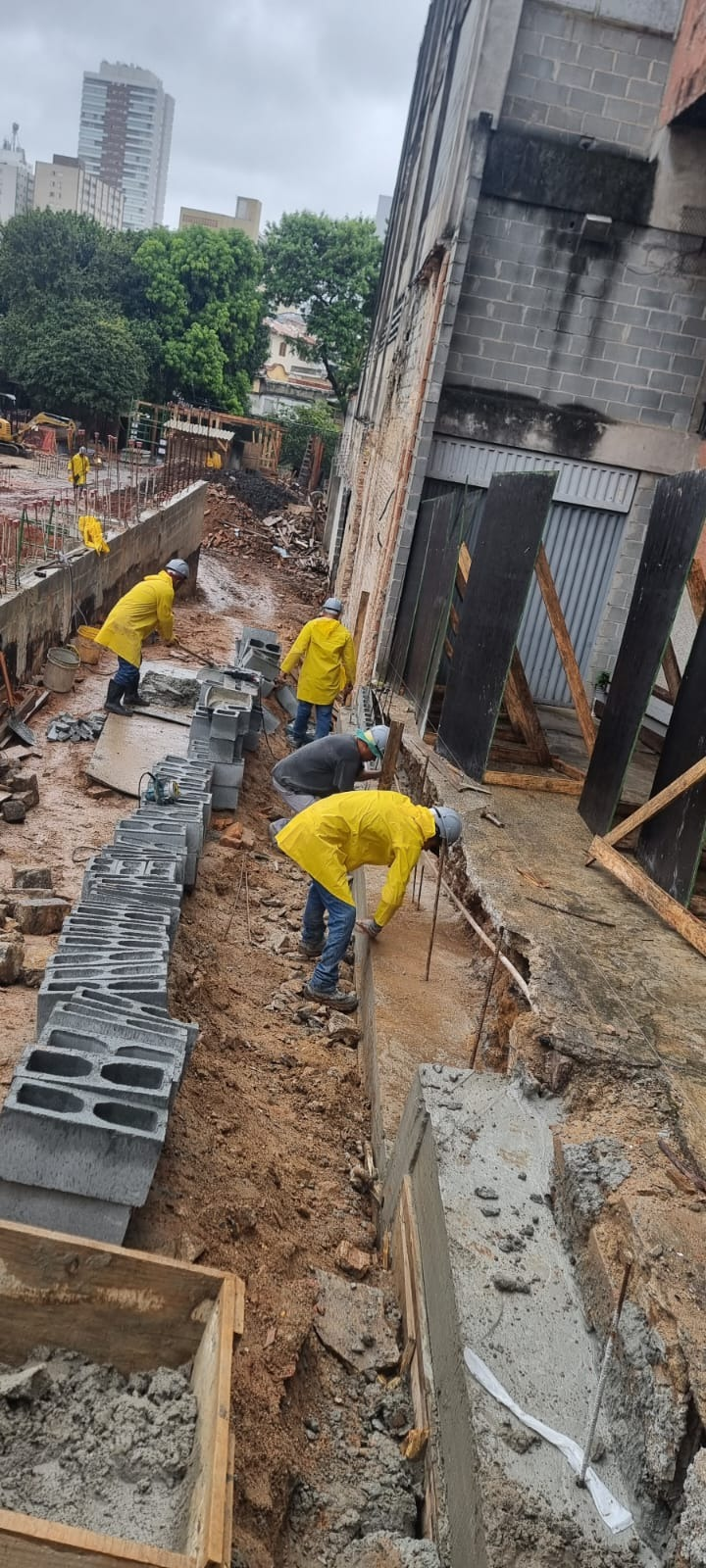 Equipe executando alvenaria estrutural em dia de chuva